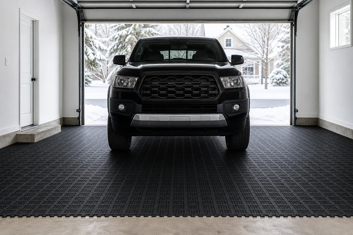 Clean residential garage with dark interlocking PVC floor tiles protecting against winter snow and salt, viewed from entrance