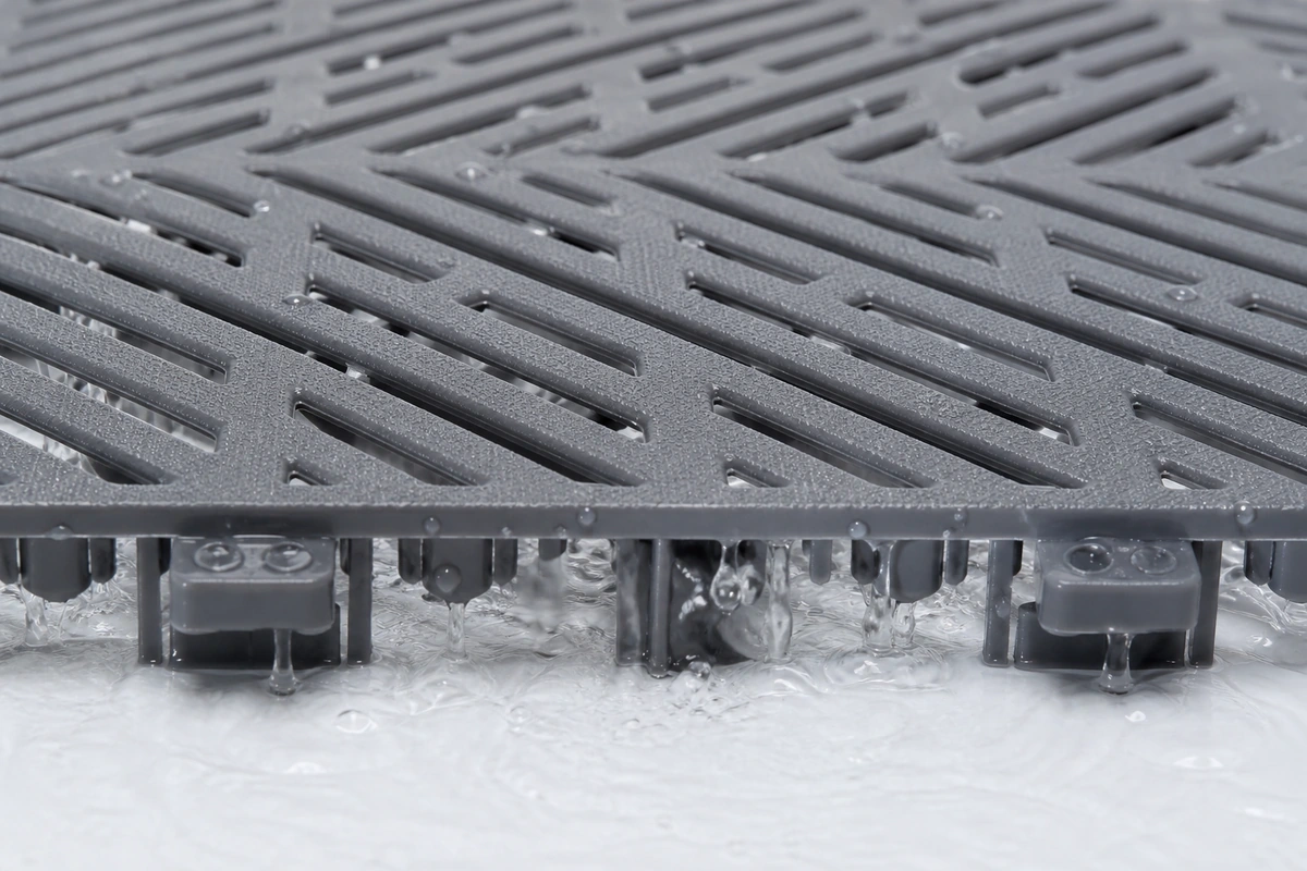 Close-up of vented drain PVC garage tile showing water draining through the open grid holes