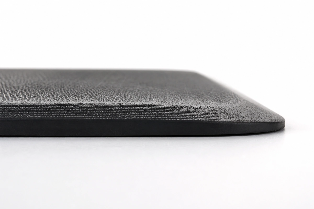 Close-up of anti-fatigue mat beveled edge showing gradual transition preventing trip hazards for elderly and children
