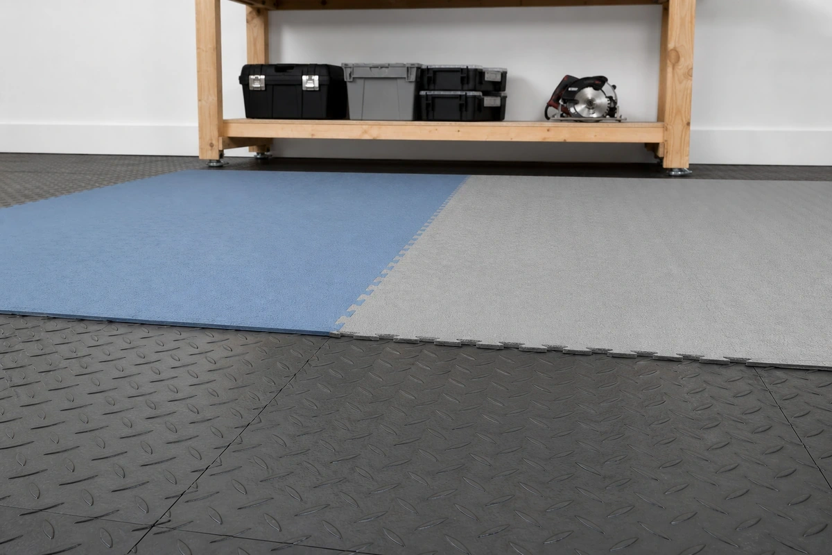 Person standing at workshop workbench on foam anti-fatigue mats layered over PVC floor tiles